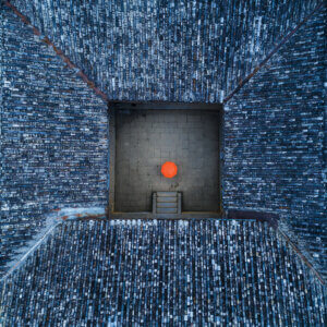 aerial view of an asian courtyard surrounded by blue featuring a single orange umbrella in the middle