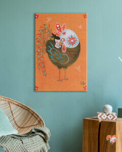 Illustration of patterned rooster hugging a small child on an orange background hanging in a teal-toned room with wicker chair