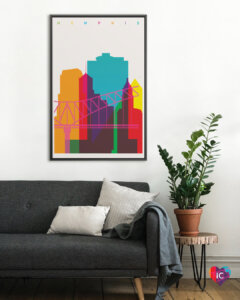 Minimalist graphic of outline of Memphis skyline and bridge in multiple colors on a beige background hanging on a wall in a living room with a black couch and potted plant