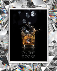 Photo of a rocks glass with scotch in it and diamonds falling into it on a black background with text that says &quot;On the rocks&quot;