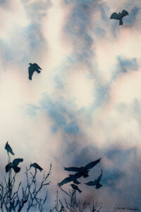 Crows flying in clouds over tops of dead tree branches