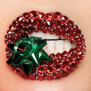 Female lips encrusted with red gemstones and a green bow between the teeth