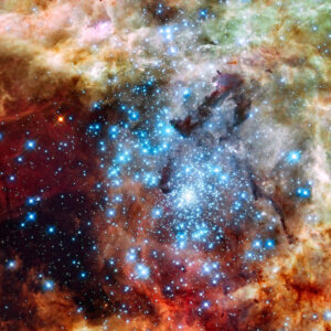 Photo of a cluster of bright blue star surrounded by colorful gases in space