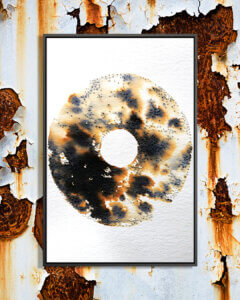 An abstract, disc-like shape with a rusted or burnt texture in black and brown on a white background