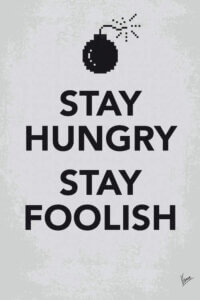 Gray print with black text that says "Stay Hungry Stay Foolish" by a pixelated bomb icon over it