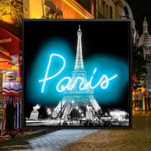 Black and white image of the Eiffel Tower lit up at night with neon blue text overlaid that says "Paris"