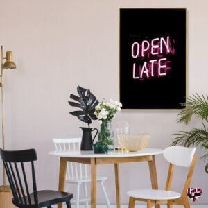 Neon pink text that says "Open Late" over a dark background, framed in gold on a wall in a dining room