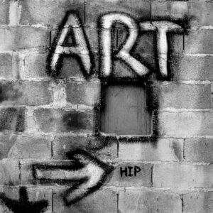 Gray brick wall with word "Art" and an arrow pointing to the word "Hip" graffitied on it