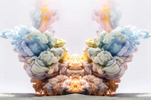 A symmetrical, colorful cloud of smoke in blue, green, pink, purple, and yellow