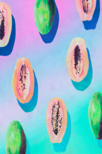 “Fruit XI” by Artist Name shows pink and green papayas on a purple and blue ombre background.