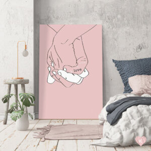 Graphic of two held hands with the word "love" written on them against a pink background leaned on a wall in a neutral colored bedroom