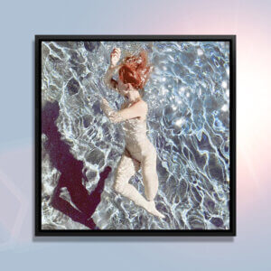 Floating II by Lola Mitchell showcases a woman with red hair wearing skin-colored undergarments while floating underwater