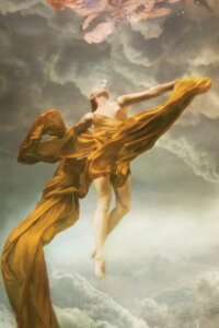 Heavens by Lola Mitchell showcases a woman floating underwater wearing a yellow dress with fabric flowing around her