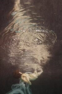 Reflections II by Lola Mitchell showcases a woman underwater while wrapped in a gray-white fabric