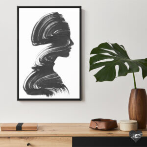Wall art of a womans profile in black brushstroke by Andreas Lie above a desk and plant