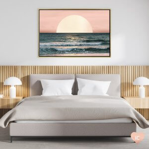 Framed wall art of a sunset over the ocean by Nature Magick above a gray bed