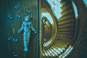 Spaceman art of an astronaut surrounded by blue butterflies laying by a spiral staircase by iCanvas artist Karen Jerzyk