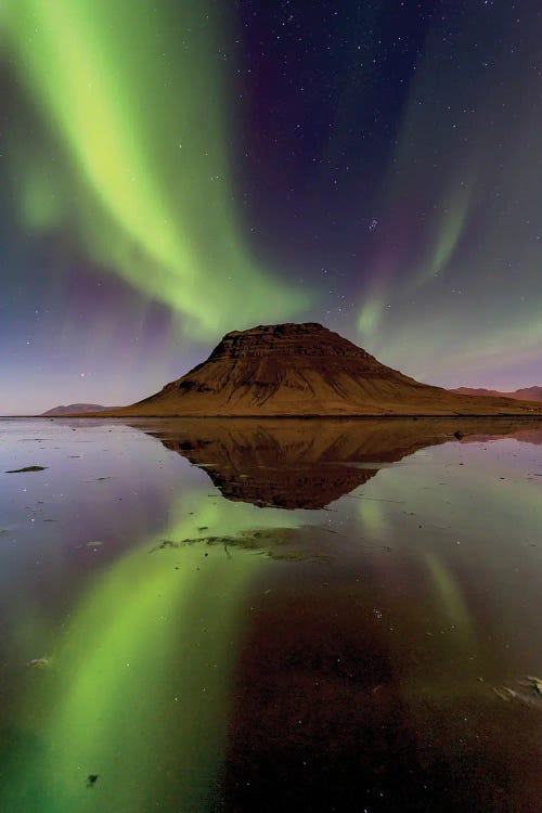 Photography of a mountain peak with green northern lights above and reflecting below by Maura La Malva