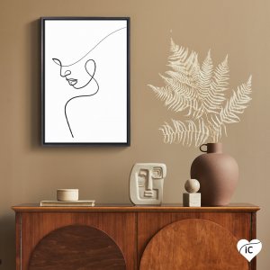 Framed black and white one line drawing of a woman’s profile mounted above a brown cabinet