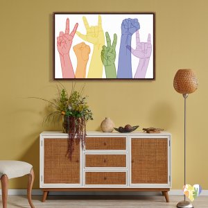 Framed pride art against yellow wall of six different hands in different gestures in red, orange, yellow, green, blue and purple