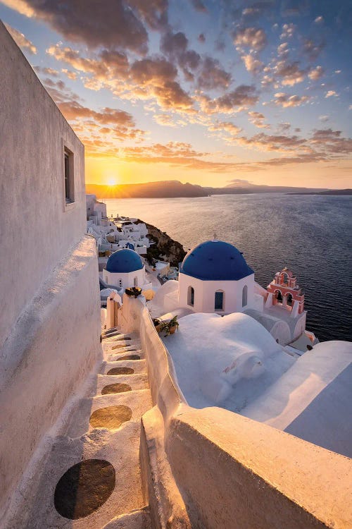 Photograph of white and blue architecture in front of sunset above sea in Santorini, Greece by Chano Sanchez