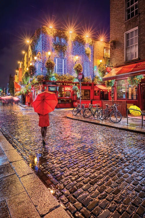 Photograph of woman in red coat with red umbrella walking streets cobblestone streets of Dublin by Chano Sanchez