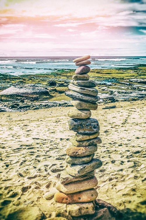 Beach photography of a stack of rocks in the sand in front of ocean and pink sky by new creator Joseph S. Giacalone