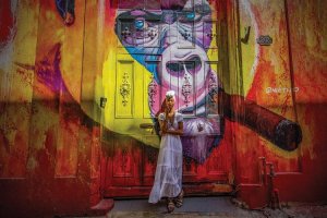 Raw photography featuring a woman smoking in front of a colorful mural of an ape smoking by iCanvas artist Robin Yong