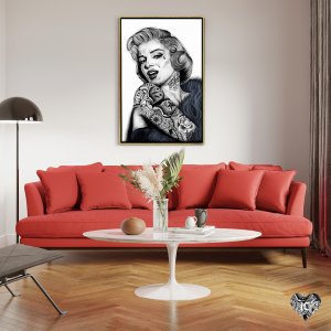 Framed tattoo wall art of Maryilyn Monroe by icanvas artist Inked Ikons mounted above red couch