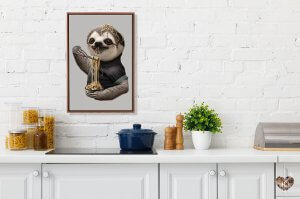 Framed animal wall art of a sloth eating ramen above kitchen counter by icanvas artist Adam Lawless