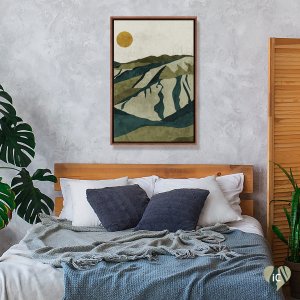 Framed wall art of green and blue mountain and yellow sun above bed by Phung Banh