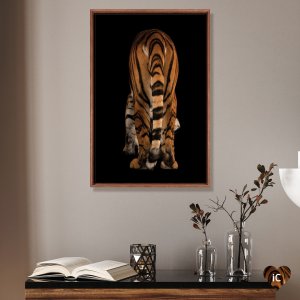 Framed photograph of a Malayan tiger's tail and backside mounted above table with vases and book by iCanvas artist Joel Sartore