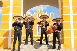 Hispanic Heritage art of mariachi band playing in front of yellow building by iCanvas artist Matteo Colombo