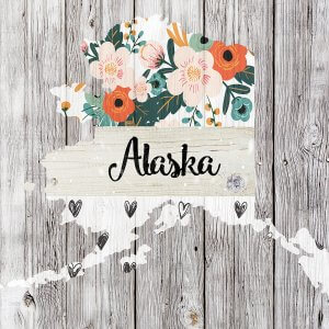 Outline of Alaska filled with flowers and hearts on wood background.
