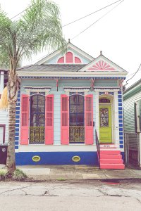 Light blue house with pink shutters, a green door, and pink stairs.