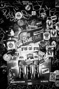 Black and white photo of many stickers on graffiti filled wall.