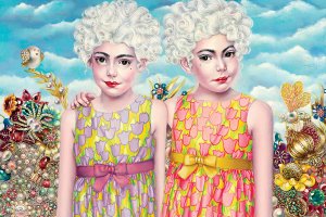 Two twins with powdered wigs and floral dresses with shiny jewelry in the background.