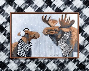 Two smiling moose wearing black and white scarves on a snowy day.