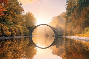 Autumn trees surrounding a bridge over reflective water