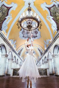 Ballerina dancing in room with columns and chandelier