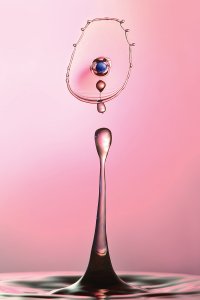 Water droplet with blue gem in front of pink background