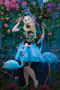 Alice in Wonderland in blue dress with two blue flamingos in front of floral background