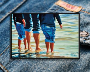 Three people standing at edge of water wearing rolled up jeans