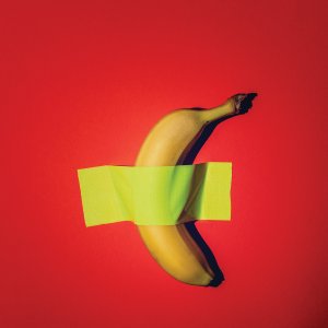 Banana taped to a red wall with bright yellow tape