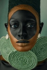 portrait of african woman with black face paint and green neck accessories