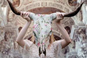 Woman holding floral skull in front of her face