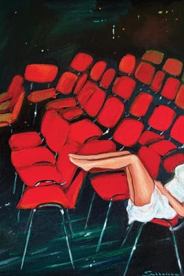 woman's legs posing up among red theater seats