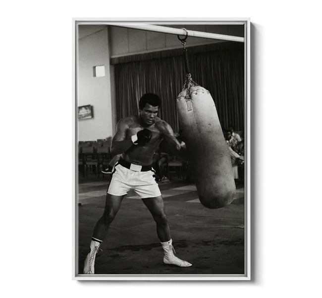 Black man in white shorts and boxing gloves hitting a punching bag