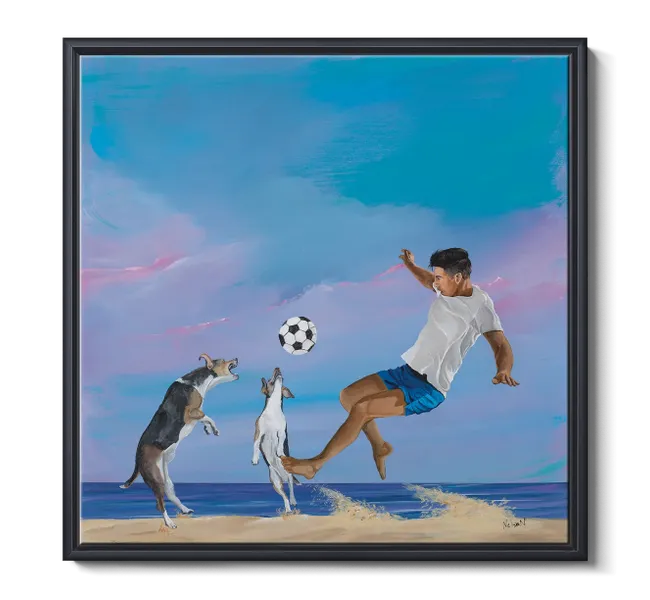 Boy kicking soccer ball with two dogs on the beach