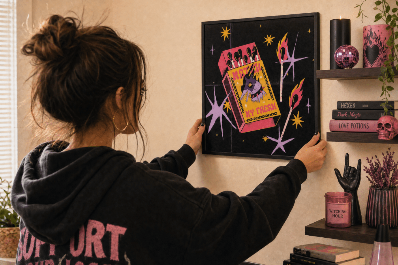 woman hanging art on dorm room wall